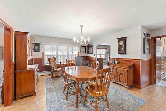 dining space featuring a wainscoted wall, an inviting chandelier, a wealth of natural light, and wallpapered walls