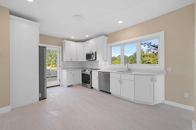 kitchen featuring stainless steel appliances, a sink, light countertops, and a healthy amount of sunlight