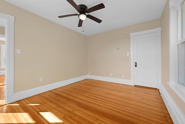 empty room with baseboards, ceiling fan, and light wood-style floors