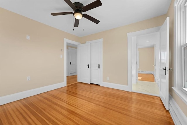 unfurnished bedroom with baseboards, a baseboard radiator, and light wood-style floors