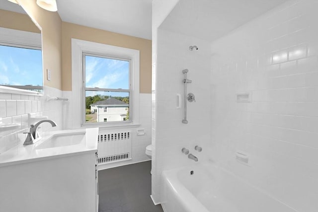 bathroom featuring toilet, tile walls, radiator heating unit, and bathing tub / shower combination