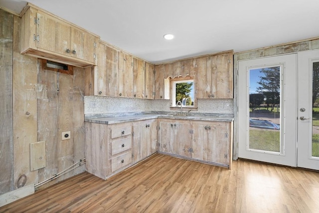 kitchen featuring light countertops, light wood-type flooring, a sink, and decorative backsplash