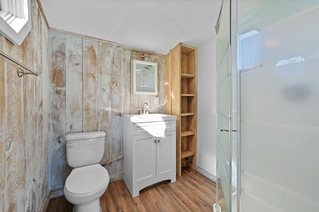 bathroom featuring a shower, vanity, toilet, and wood finished floors