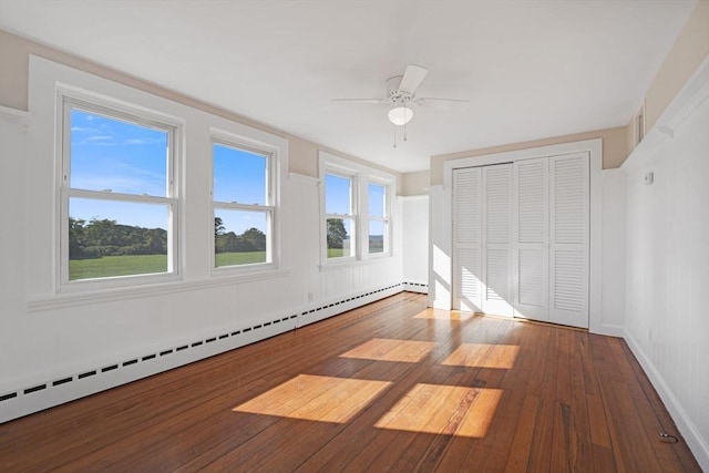 unfurnished bedroom with a baseboard radiator, a closet, a ceiling fan, and hardwood / wood-style floors