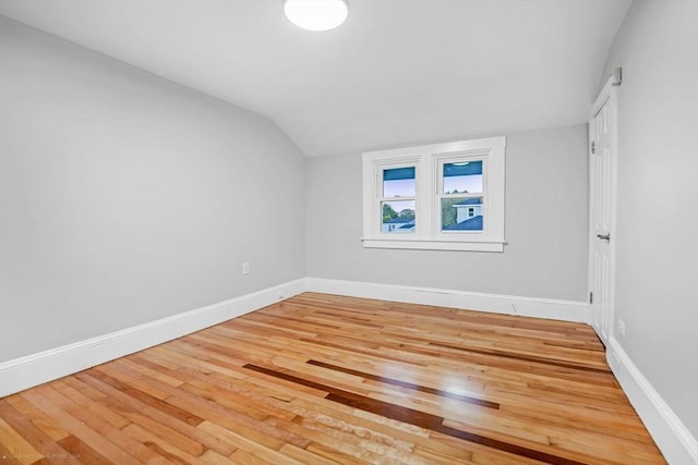 unfurnished bedroom featuring baseboards, vaulted ceiling, and hardwood / wood-style floors