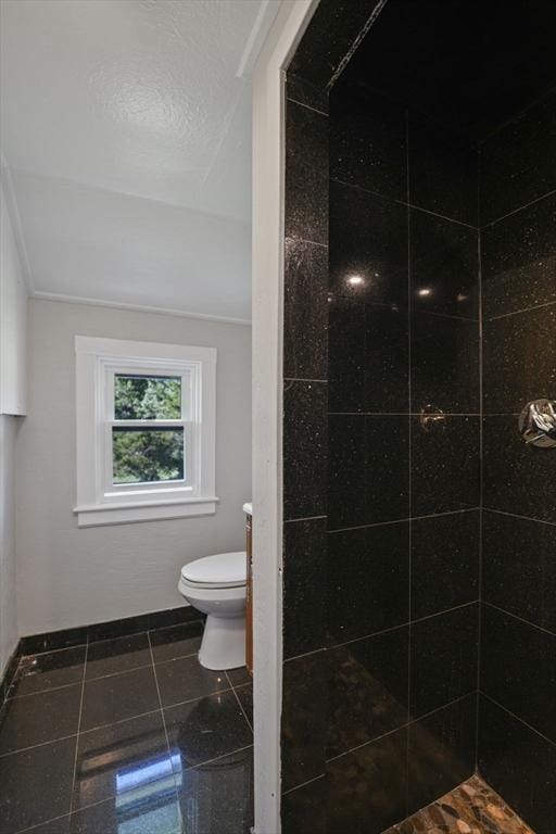 full bathroom featuring a tile shower, toilet, and tile patterned floors