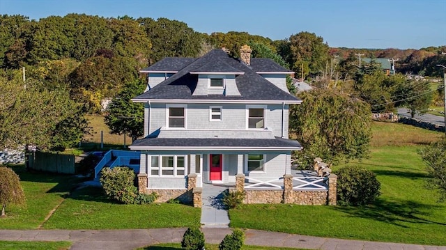 view of front facade featuring covered porch, a chimney, and a front lawn