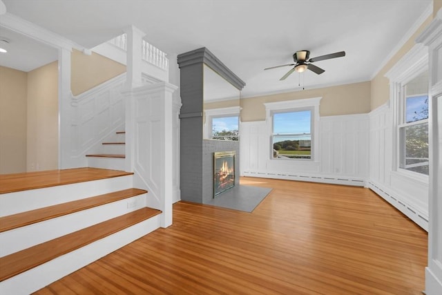 unfurnished living room with a baseboard heating unit, stairway, a multi sided fireplace, and light wood-style flooring