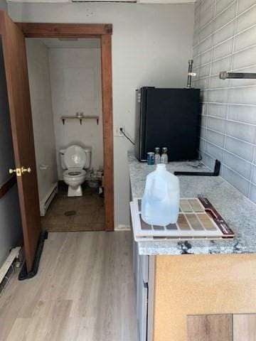 bathroom featuring hardwood / wood-style flooring, toilet, and baseboard heating