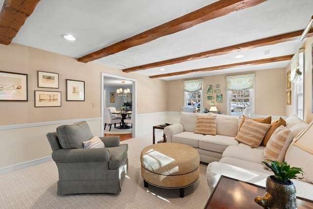 carpeted living room featuring beam ceiling and a chandelier