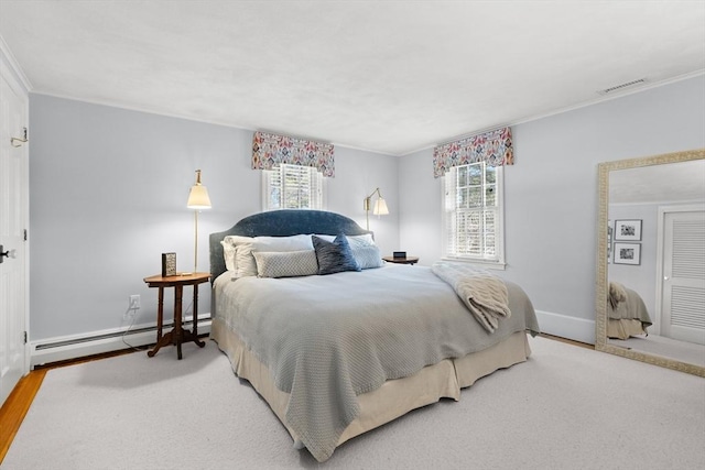 bedroom featuring crown molding, wood-type flooring, and a baseboard heating unit