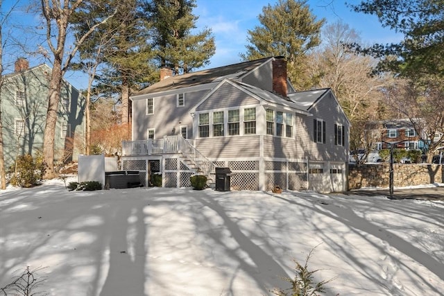 snow covered property with a wooden deck and a garage