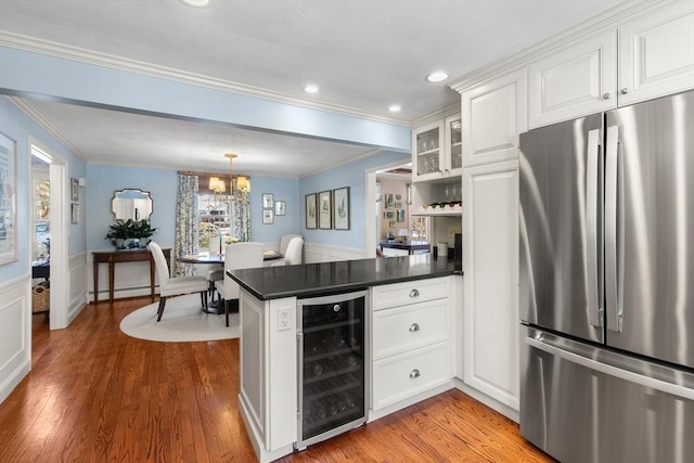 kitchen with wine cooler, kitchen peninsula, stainless steel refrigerator, and white cabinets