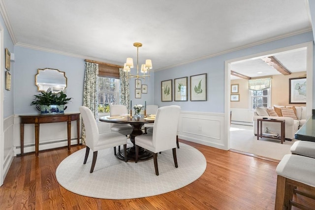 dining room with hardwood / wood-style floors, crown molding, a baseboard radiator, and a chandelier