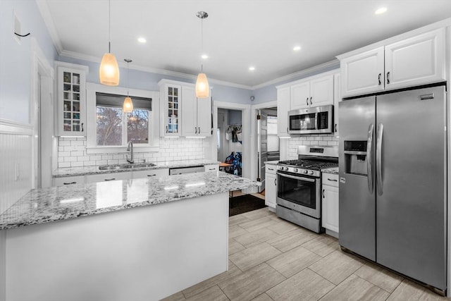 kitchen with appliances with stainless steel finishes, sink, pendant lighting, and white cabinets