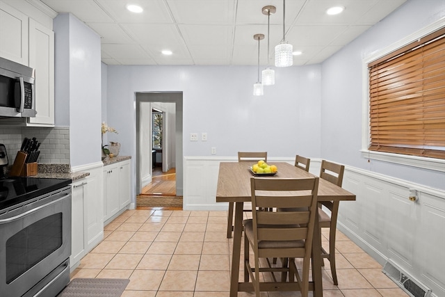 dining space with a paneled ceiling and light tile patterned flooring