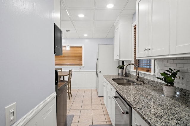 kitchen with stone counters, white cabinetry, sink, hanging light fixtures, and stainless steel dishwasher