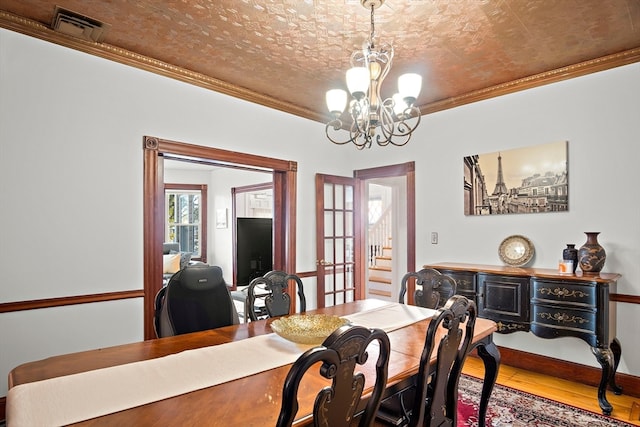 dining space featuring french doors, an inviting chandelier, crown molding, a textured ceiling, and wood-type flooring