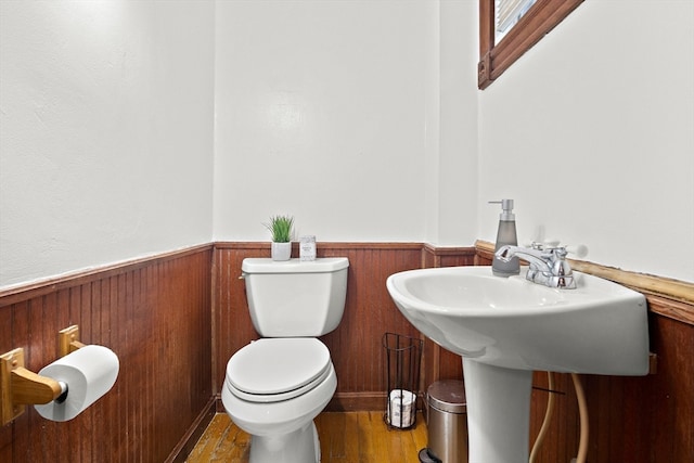 bathroom featuring hardwood / wood-style flooring, toilet, and wooden walls