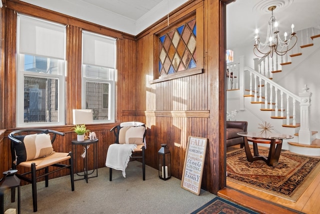 living area with wood walls, crown molding, carpet floors, and an inviting chandelier