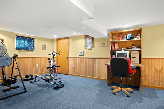 workout room featuring carpet flooring and wooden walls