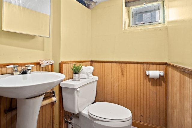 bathroom with toilet and wood walls