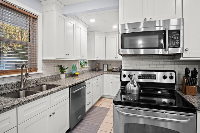 kitchen featuring decorative backsplash, appliances with stainless steel finishes, light stone counters, sink, and white cabinets