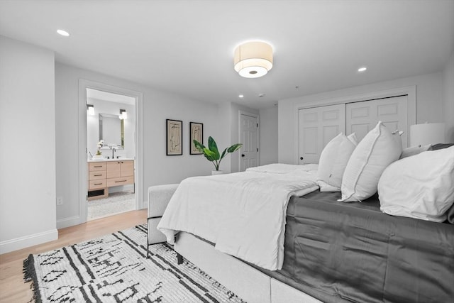 bedroom with ensuite bathroom, sink, light hardwood / wood-style floors, and a closet