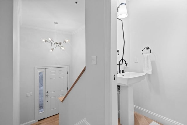 bathroom with crown molding, an inviting chandelier, and hardwood / wood-style floors