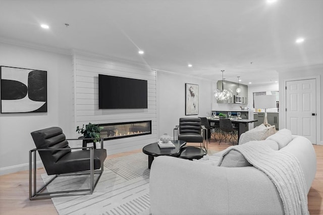 living room with light hardwood / wood-style floors, ornamental molding, and a large fireplace