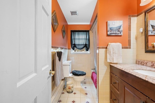 full bathroom featuring tile walls, visible vents, toilet, vanity, and tile patterned floors