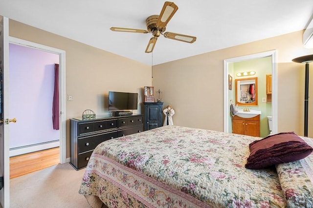 bedroom featuring ensuite bathroom, a baseboard radiator, light colored carpet, a sink, and a ceiling fan