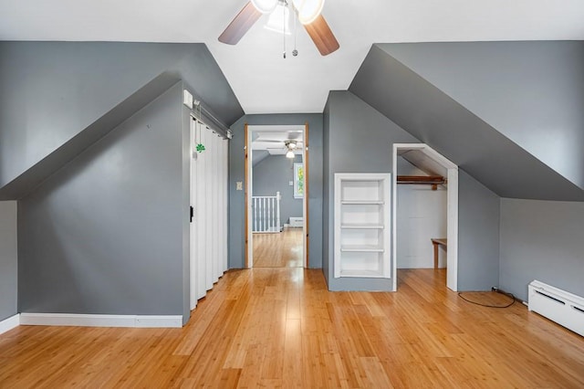 additional living space with light wood-style floors, lofted ceiling, ceiling fan, and a baseboard radiator