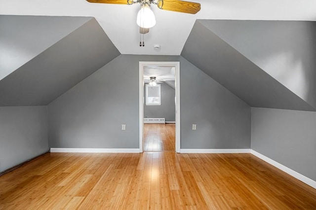 bonus room with a ceiling fan, baseboard heating, light wood-style flooring, and baseboards