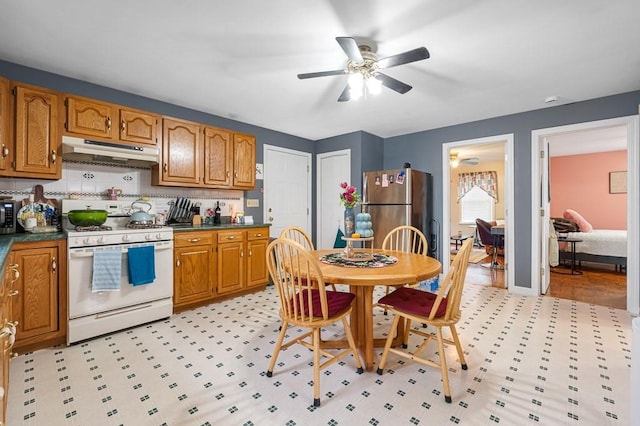 kitchen featuring dark countertops, under cabinet range hood, appliances with stainless steel finishes, and brown cabinetry