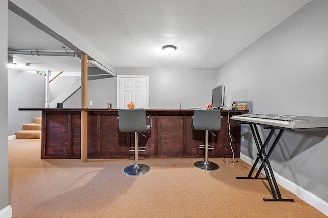 bar with stairs, a bar, light colored carpet, and baseboards