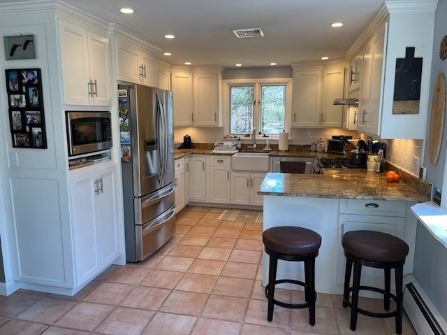 150 Sagamore St, Hamilton, MA 01982 - kitchen with appliances with stainless steel finishes, a peninsula, a baseboard radiator, white cabinetry, and recessed lighting