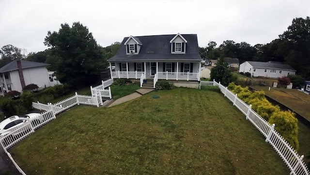 new england style home with fence private yard, covered porch, and a front yard