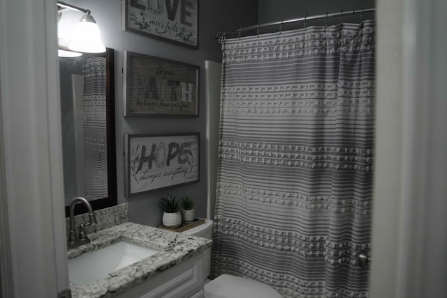 bathroom with curtained shower, vanity, and toilet