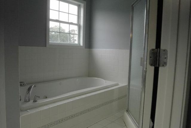 bathroom featuring a stall shower, a bath, and tile patterned floors