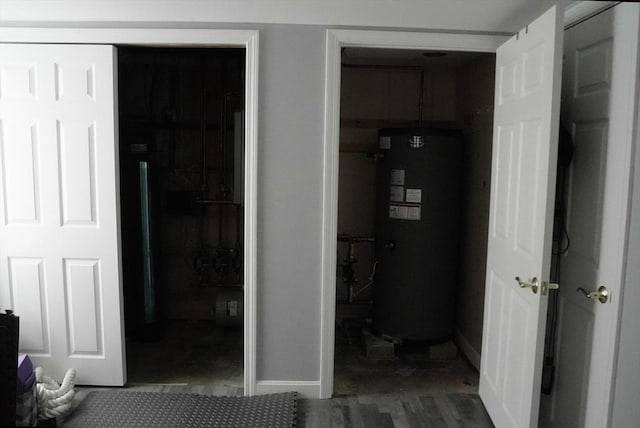 hallway with dark wood-style flooring, water heater, and baseboards