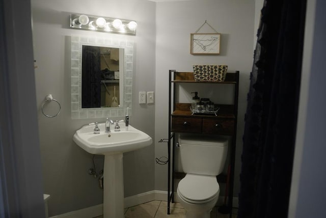 bathroom with toilet, baseboards, a sink, and tile patterned floors