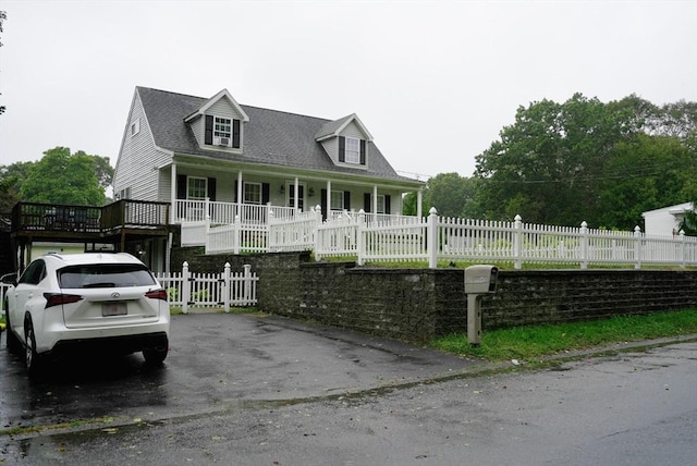 cape cod-style house with a fenced front yard and a porch