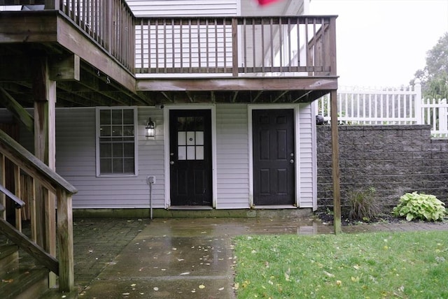 view of exterior entry with fence and a balcony