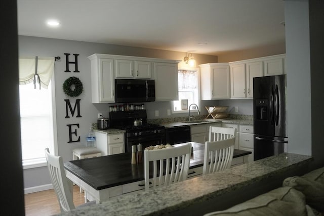 kitchen with black appliances, white cabinets, and a sink