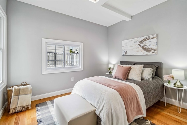 bedroom with light wood-type flooring and beamed ceiling