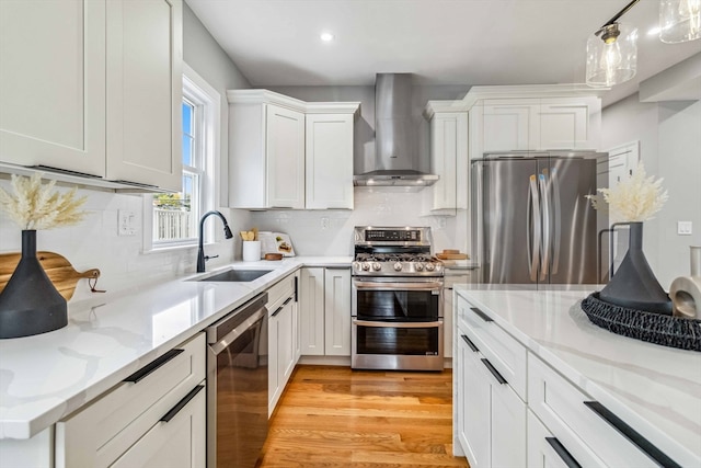 kitchen with sink, white cabinets, wall chimney range hood, light hardwood / wood-style flooring, and stainless steel appliances