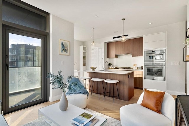 kitchen with an island with sink, a kitchen bar, light countertops, stainless steel appliances, and modern cabinets