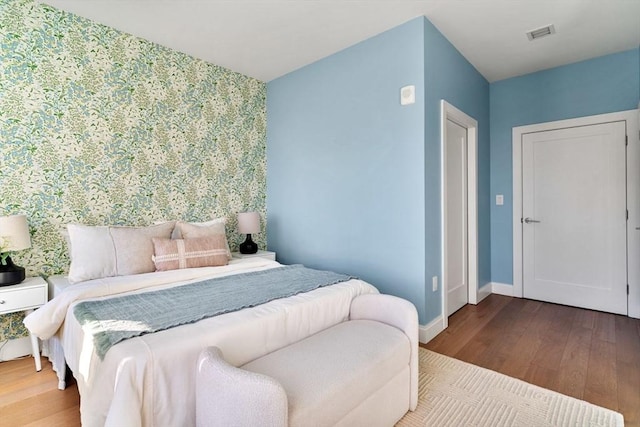 bedroom with visible vents, baseboards, and wood finished floors