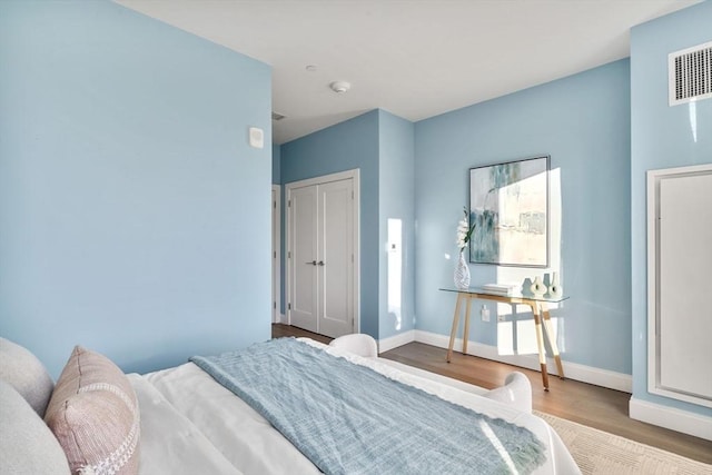 bedroom featuring wood finished floors, visible vents, and baseboards